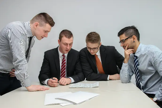 Four people looking at paper on a table
